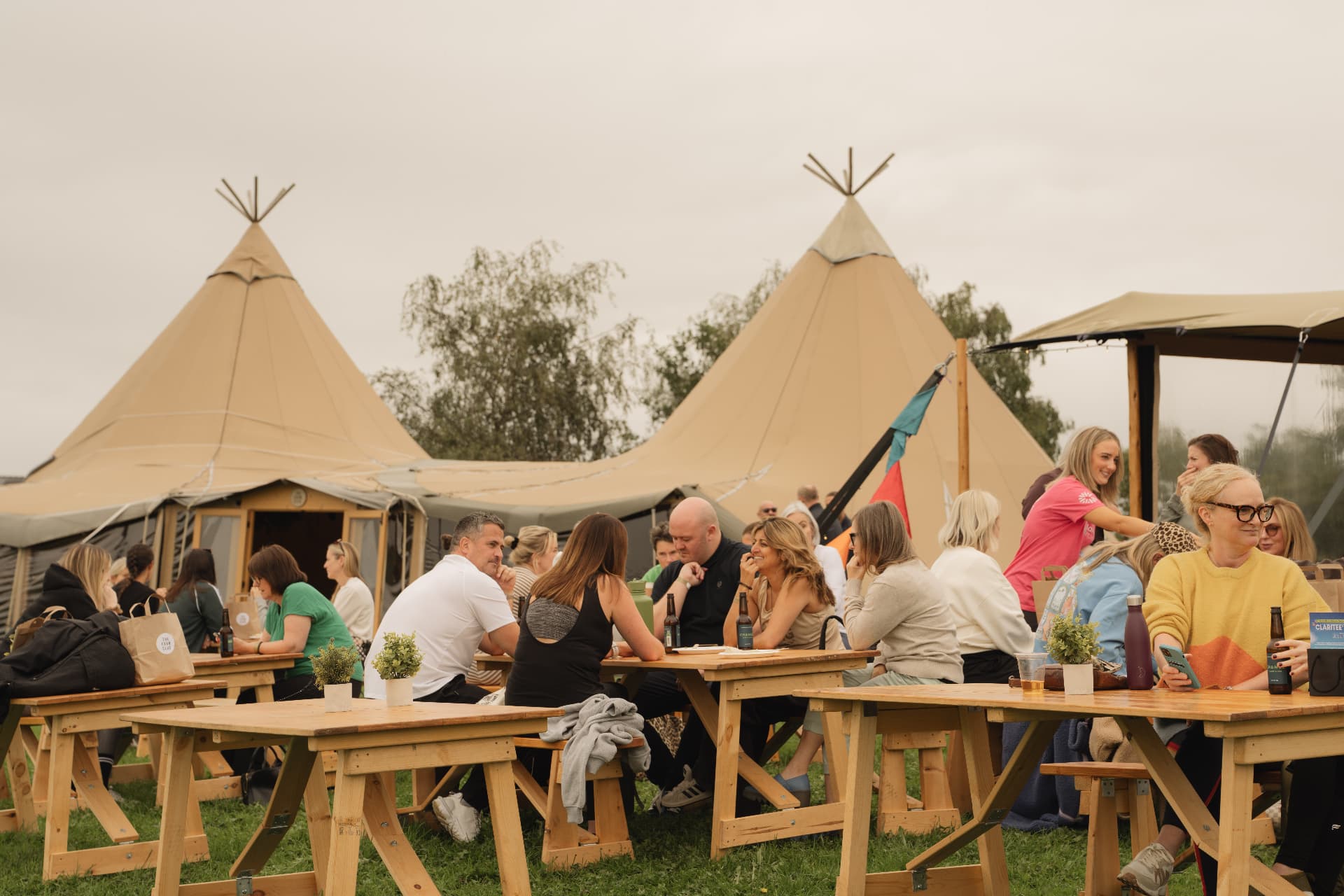 Guests sharing lunch at picnic tables beside the tipis