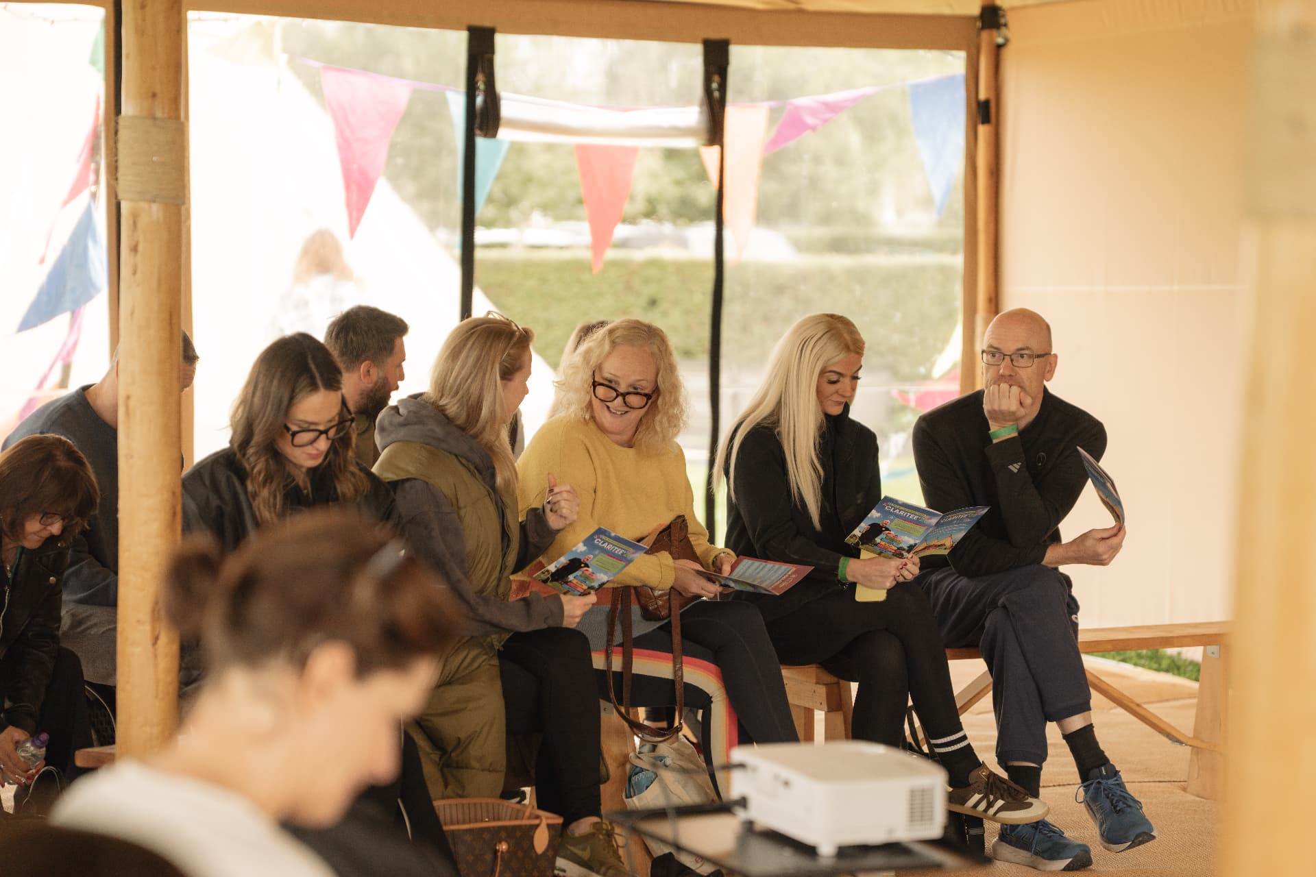 Guests reading programmes and chatting in the tent