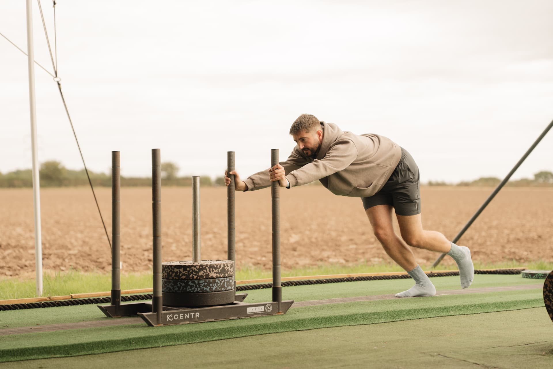 A guest pushing a weighted sled beside the fields